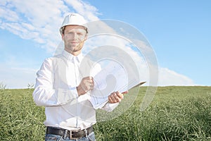 Happy working architect in white helmet with documentation smiling.