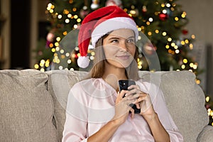 Happy Xmas girt in red Santa cap holding smartphone