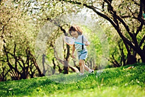 Happy 3 years old child boy catching butterflies with net on the walk in sunny garden or park
