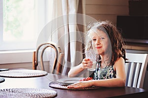 Happy 8 years old child girl having breakfast in country kitche photo