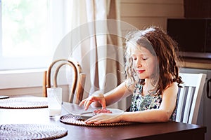 Happy 8 years old child girl having breakfast in country kitchen