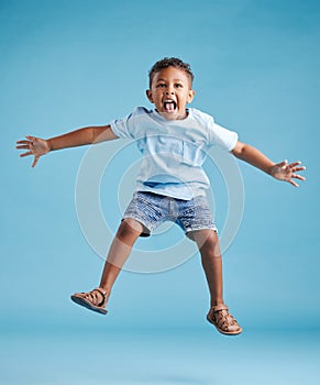 Happy young adorable little hispanic boy jumping in the air, isolated on blue background. Funny preschooler kid