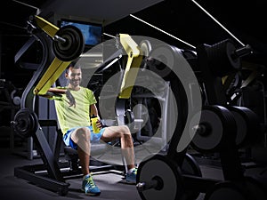 Happy young adult bodybuilder doing weight lifting in gym.