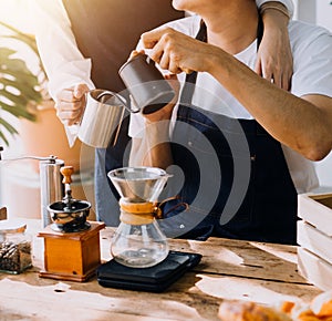 Happy young adult couple making breakfast and drinking coffee together in cozy home kitchen in morning at home. Preparing meal and
