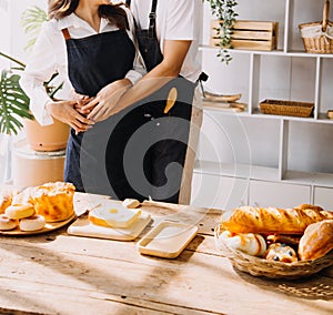 Happy young adult couple making breakfast and drinking coffee together in cozy home kitchen in morning at home. Preparing meal and