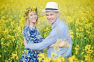 Happy young adult couple at spring yellow field