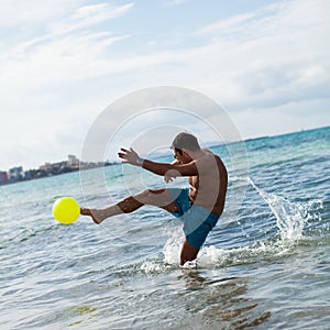 Happy young adult man playing beach ball in summer