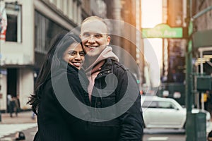 Happy young adult multicultural couple in love hugging and smiling on New York City street.