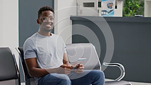 Happy young adult waiting in hospital lobby to meet with general practitioner