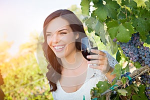 Happy Young Adult Woman Enjoying Glass of Wine Tasting In The Vineyard