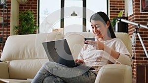 Happy young adult woman inserting credit card credentials on on shopping site for online payment