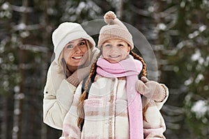 Happy young affectionate mother embracing daughter in winterwear