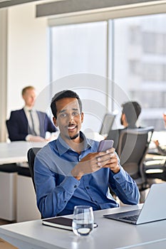 Happy young African American business man using cell phone in office. Portrait