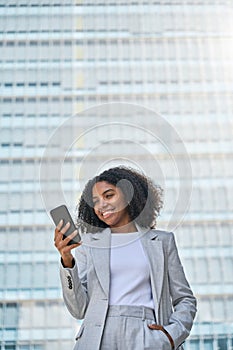 Happy young African American business woman using cell phone outdoors.