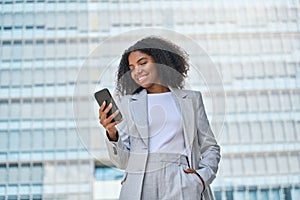 Happy young African American business woman using phone outdoors.