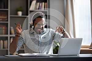 Happy young african american businessman enjoying listening energetic music.