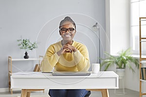 Happy young African American businesswoman sitting at working desk with laptop at home
