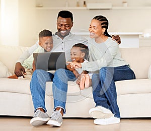 Happy young african american family sitting together and using laptop. Curious cute little girl and boy sitting with