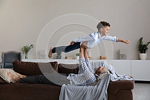 Happy young African American father lifting in air laughing son.