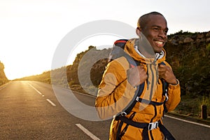 Happy young african american male hiker walking on road during sunrise
