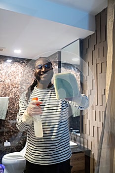 Happy young African American man cleaning the glass in the apartment. Cleaning maintain cleanliness in with towel and