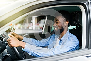 Happy young african american man driving a car on street roads