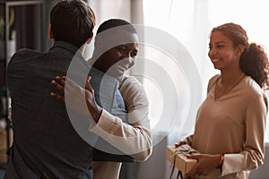 Happy young African American man giving hug to his buddy