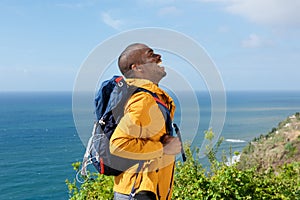 Happy young african american man hiking in nature with backpack