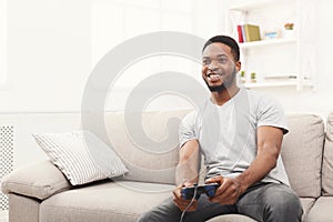 Happy young african-american man at home playing video games
