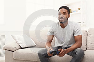 Happy young african-american man at home playing video games