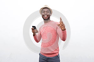 Happy young african american man listening to music with mobile phone and earphones against white background