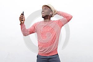 Happy young african american man listening to music with smart phone and earphones against white background