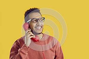 Happy young African American man talking to friends on landline phone and smiling