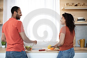 Happy young african american man and woman preparing salad with organic vegetables together