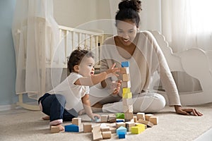 Happy young african american mother playing cubes with baby.