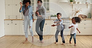 Happy young african american parents dancing with kids indoors.