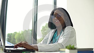 Happy young african american woman doctor with a laptop looking at camera. Smiling female physician posing in hospital