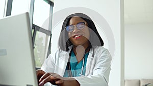 Happy young african american woman doctor with a laptop looking at camera. Smiling female physician posing in hospital