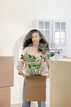 happy young African American woman is moving into new home. person stands among cardboard boxes
