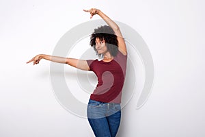 Happy young african american woman pointing at side with both hands on white background