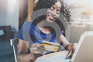 Happy young african american woman shopping online through laptop using credit card at home. Horizontal,blurred