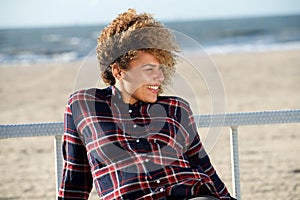 Happy young african american woman sitting at beach