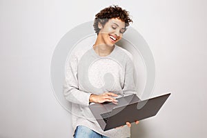 Happy young african american woman smiling by white background with laptop computer