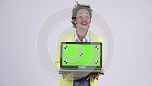 Happy young African businesswoman showing laptop and looking surprised