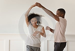 Happy young african couple holding hands dancing laughing at home photo