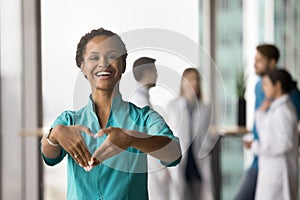 Happy young African doctor woman showing hand heart