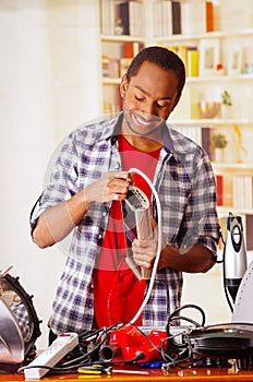 Happy Young African Ecuadorian male Technician repairing a Power Regulator