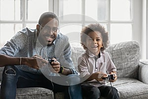 Happy young african father involved in video game with son.