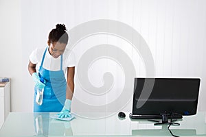 Female Janitor Cleaning Desk With Rag