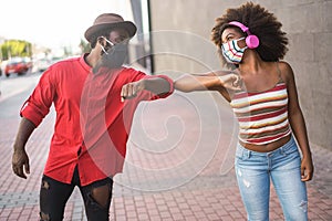 Happy young african friends bumping their elbows instead of greeting with a hug - Focus on woman eyes photo